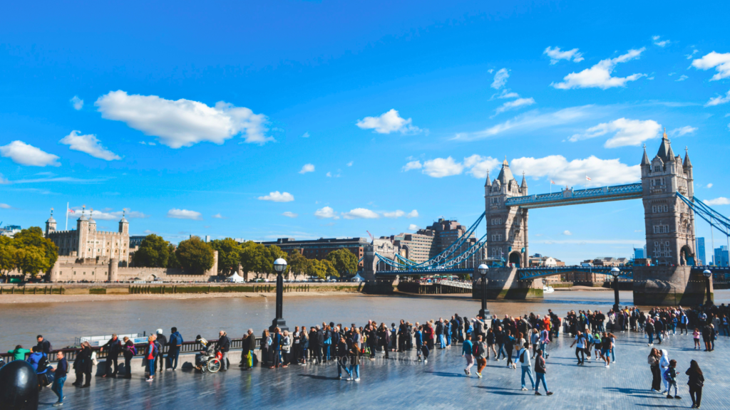 Crowds on South Bank London admiring Tower Bridge and Tower of London along the Thames riverside walk