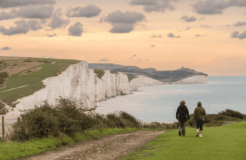 Visitors walking along the White Cliffs of Dover coastal path overlooking the English Channel during a scenic day trip from London.