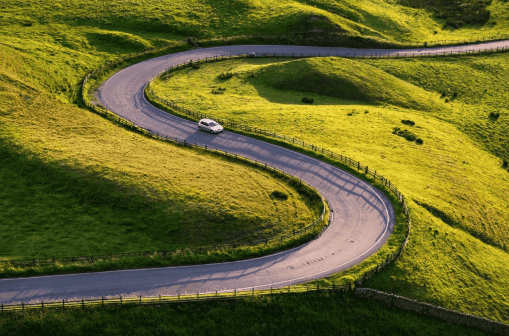 Car driving along a winding country lane through the English countryside, a scenic road trip option for exploring the best day trips from London.