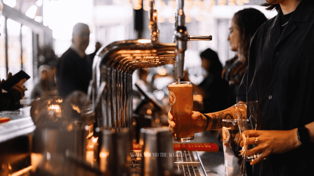 Bartender pouring a fresh pint of beer at the bar inside a traditional London pub, showcasing authentic British pub culture and the classic ordering experience.