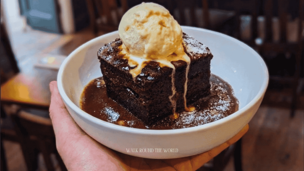 Traditional Sticky Toffee Pudding served with warm toffee sauce and vanilla ice cream in a Central London pub.
